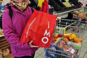 Bild 2: Eine überglückliche Kundin freut sich über eine Tasche mit haltbaren Lebensmitteln, die sie als Weihnachtsgeschenk zusätzlich geschenkt bekommen hat 